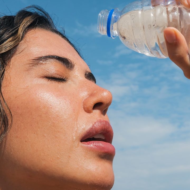 schwitzende Frau kühlt sich mit Wasser ab